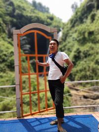 Portrait of young man standing against trees