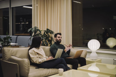 Businessman explaining strategy to female colleague while working late in office at night