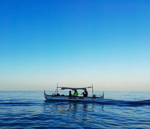 People sitting in fishing boat sailing on sea during sunset