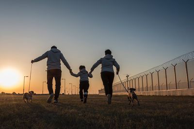 Full length of father with dog walking on landscape against sky