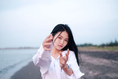 Portrait of beautiful woman gesturing while standing at beach