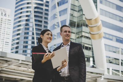 Low angle view of business people looking away while standing against building