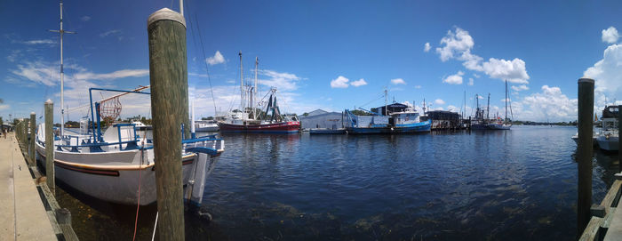 Boats moored at harbor against sky