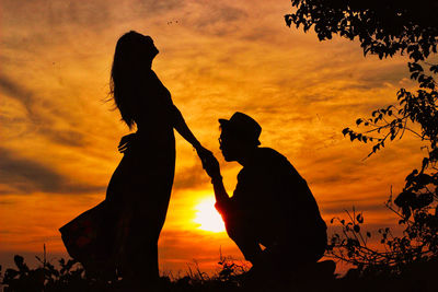 Silhouette people against orange sky during sunset
