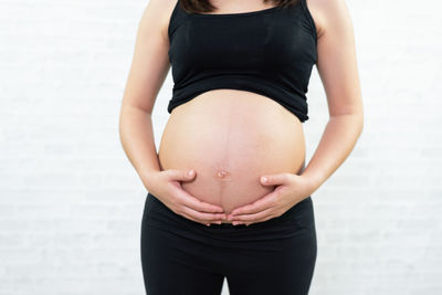 Midsection of pregnant woman touching stomach