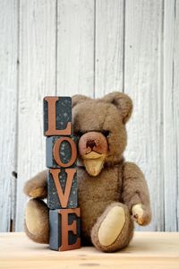 Close-up of teddy bear with love blocks on wooden table