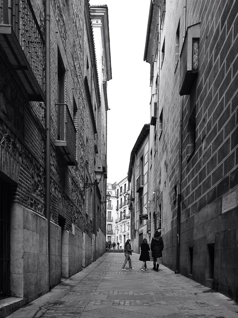 architecture, building exterior, built structure, the way forward, walking, men, street, city, person, alley, residential building, cobblestone, building, residential structure, lifestyles, city life, diminishing perspective, clear sky, rear view