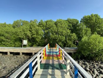 Footbridge amidst trees against clear sky