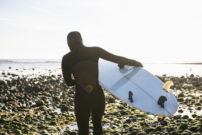 Rear view of man standing at beach against sky