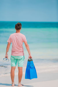 Rear view of man on beach against sky