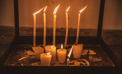 Close-up of illuminated candles on table against sky during sunset