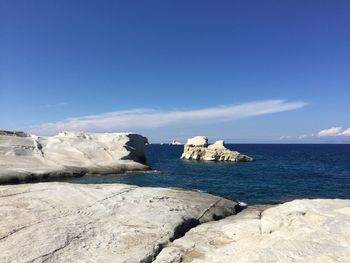 Scenic view of sea and rocks against blue sky