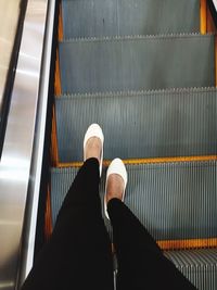 Low section of person standing on escalator