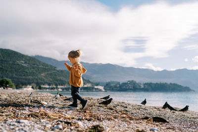 Rear view of man standing on rock against sky