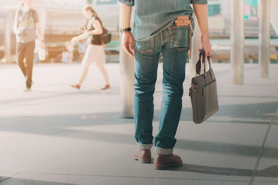 Low section of woman holding purse while standing in city