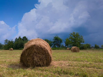 Hay bales on field against sky