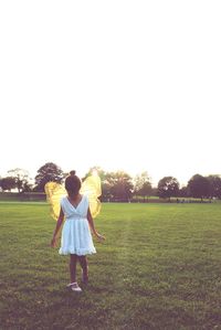 Girl walking on grass against sky