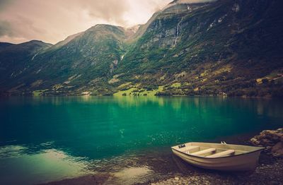Boats moored in lake against mountains