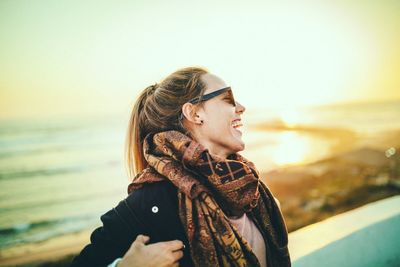Portrait of man wearing sunglasses at beach against sky during winter