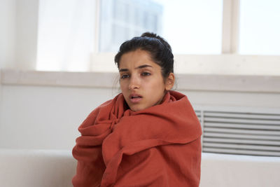 Portrait of woman standing against red wall