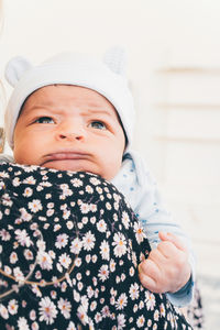 Infant boy making a funny face while relaxing on the mother's shoulder