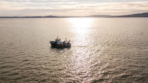 Boat sailing on sea against sky during sunset