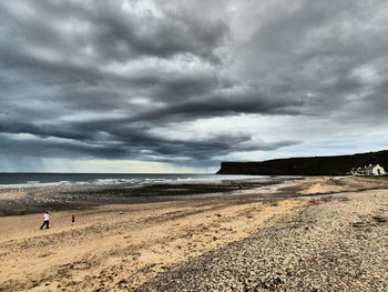 Scenic view of beach against cloudy sky