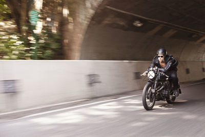 Man wearing sunglasses riding motorcycle on road