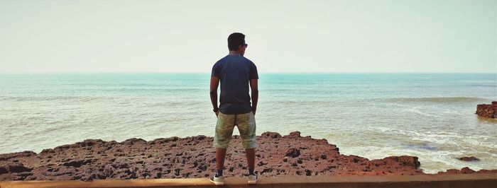 A boy stands in front of the ocean border.