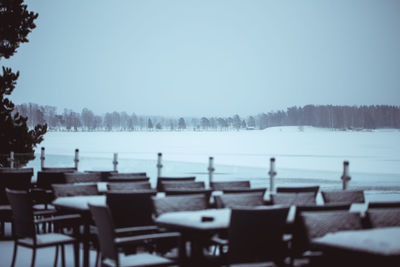 Chairs and tables against clear sky during winter