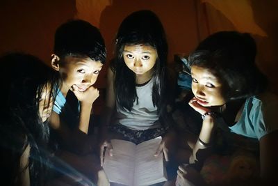 Close-up portrait of smiling siblings standing at night