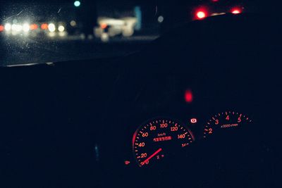 Close-up of illuminated lighting equipment on road at night