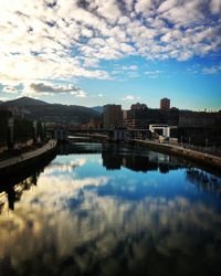 Reflection of cityscape in river against sky