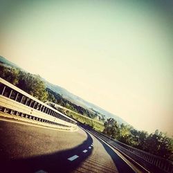 Road leading towards mountains against clear sky