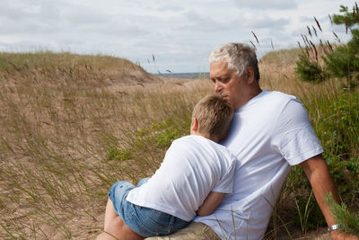 Grandfather with grandson resting on field