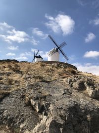 Low angle view of windmills on mountain against sky