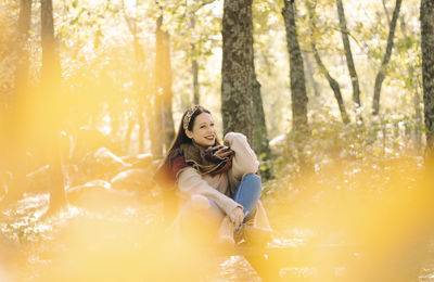 Young woman sitting on a picnic table surrounded by a forest