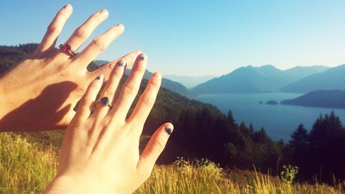 Close-up of woman hand by tree against sky