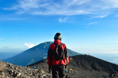 Rear view of man looking at mountains against sky