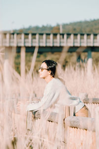 Portrait of young woman standing by railing