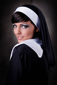 Close-up portrait of smiling nun against black background