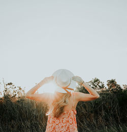 Rear view of woman standing on field against clear sky