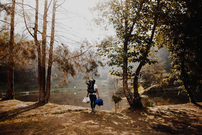 Rear view of female hiker walking at lakeshore against trees