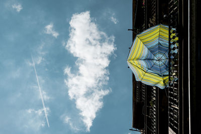 Low angle view of umbrella hanging on railing against blue sky