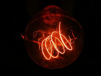 Close-up of illuminated light bulb over black background