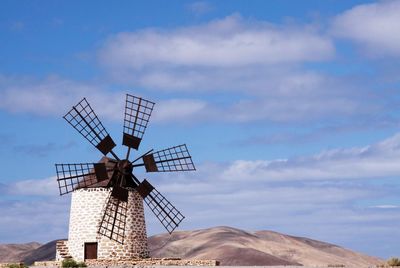 Traditional windmill on landscape against sky