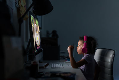 Young girl with headphones using computer at home