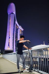 Full length of young man photographing on bridge at night