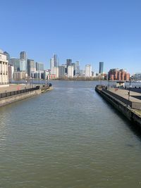 River by buildings against clear sky