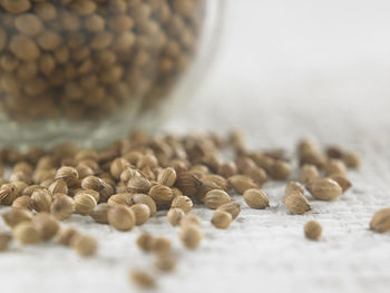 Close-up of coriander seeds in glass jar on table